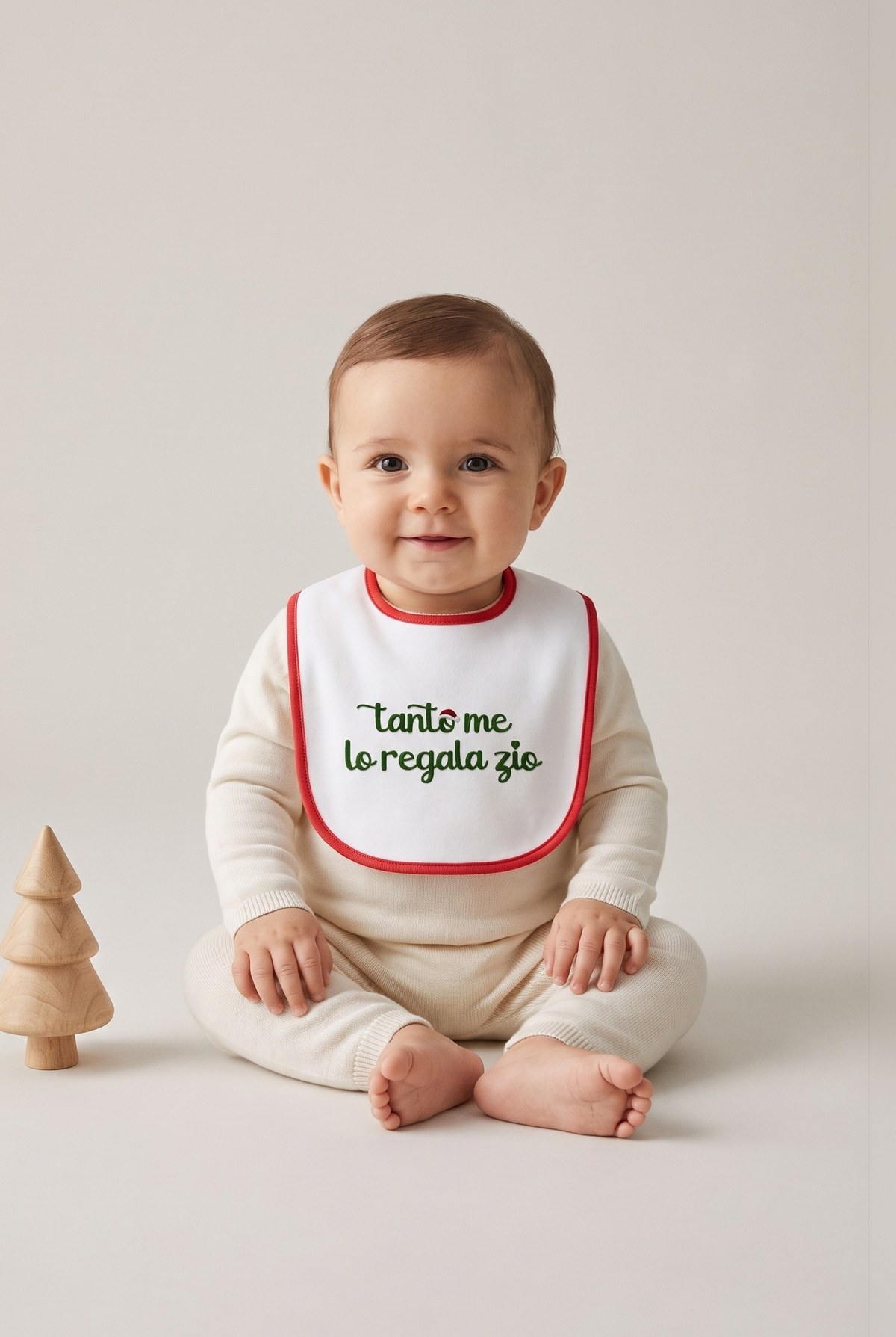 Bavetta neonato bianca con bordino rosso e ricamo verde "Tanto me lo regala zio", foto indossata - Capsule Natale MADRESPERA