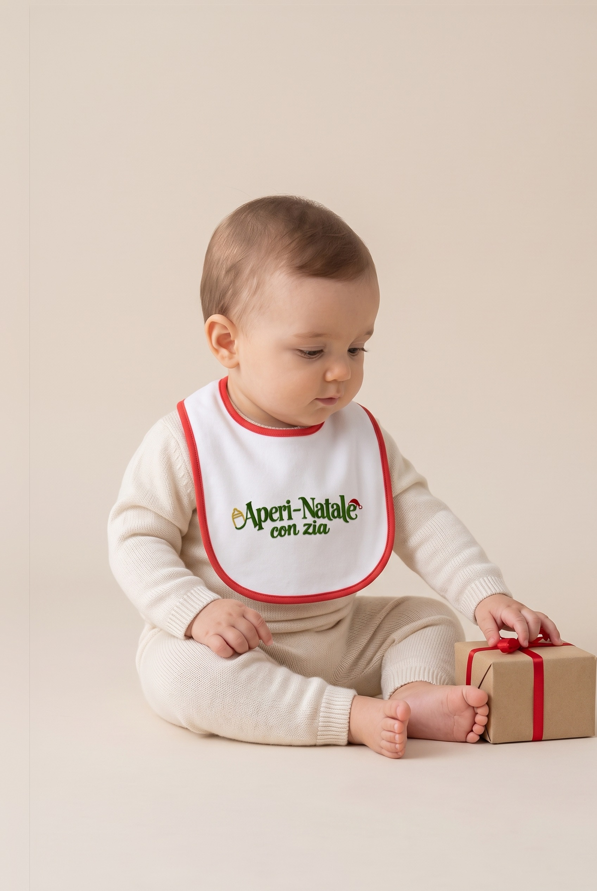 Bavetta neonato bianca con bordino rosso e ricamo verde "Aperi-Natale con zia", foto indossata - Capsule Natale MADRESPERA