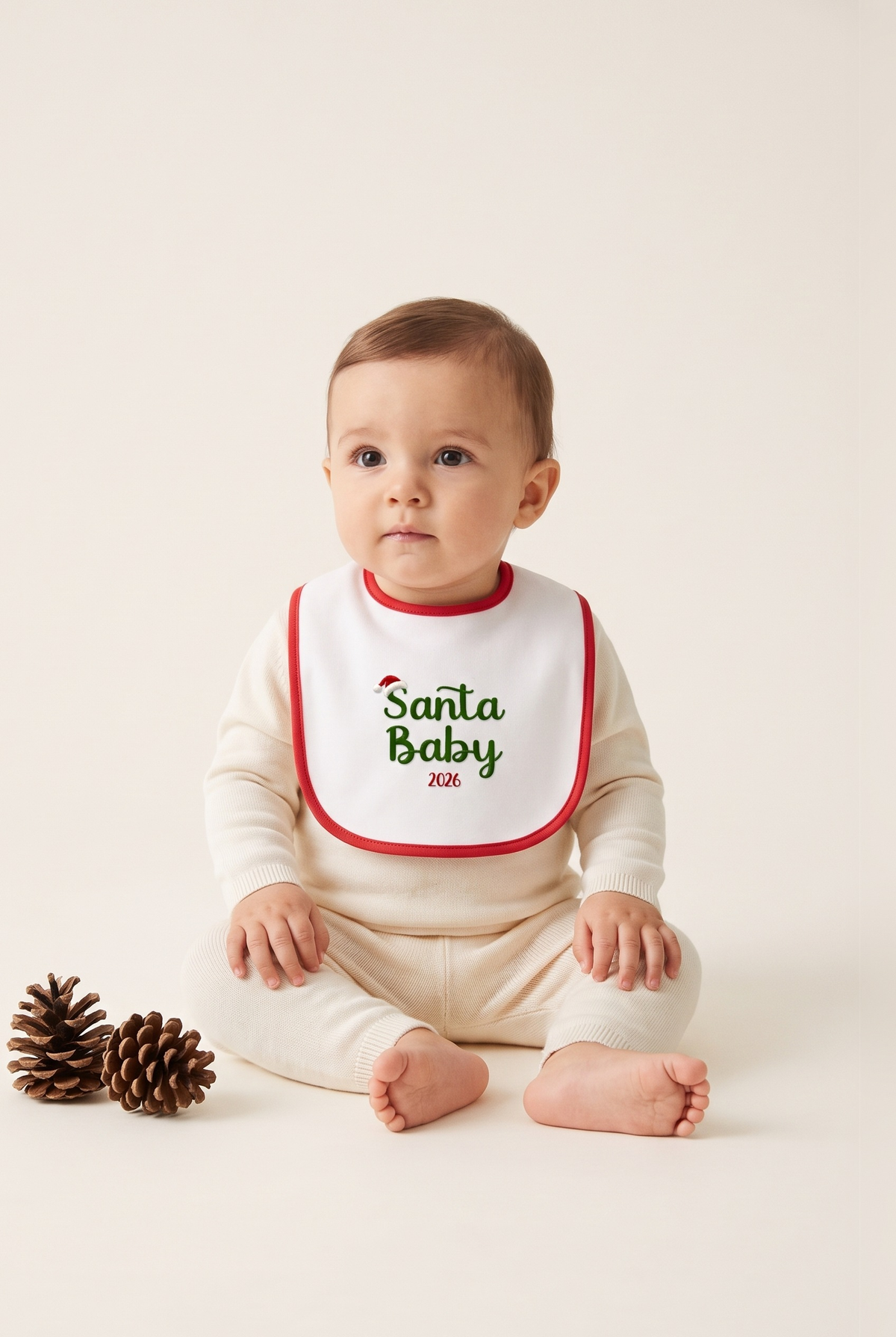 Bavetta neonato bianca con bordino rosso e ricamo verde "Santa Baby 2026", foto indossata - Capsule Natale MADRESPERA
